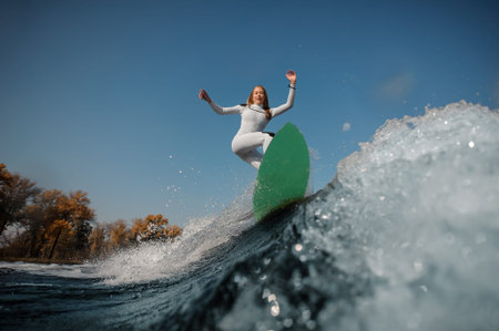 Blonde girl riding on the green wakeboard on the bending knees