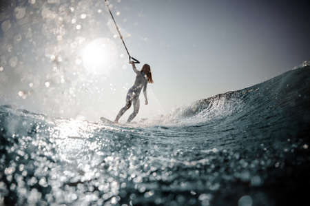 Blonde girl standing on the wakeboard holding a ropeの写真素材