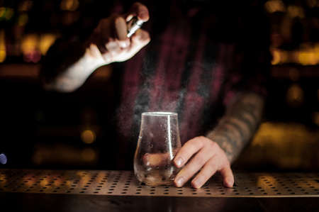 Barman sprinkling bitter into a low cocktail glassの写真素材