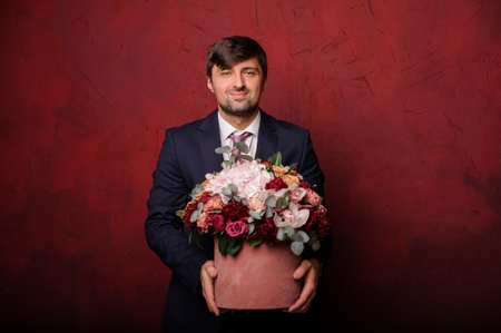 Young man holding a pink box of beautiful flowersの写真素材