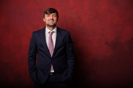 Young man standing on the background of red wallの写真素材