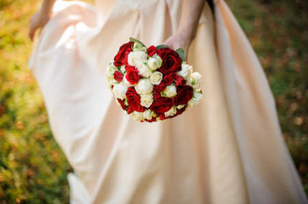 Bride in a white wedding dress holding a beauriful red roses bouquetの写真素材