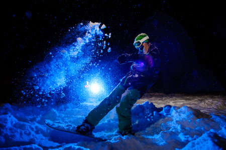 Active female snowboarder dressed in a green sportswear standind on the mountain slopeの写真素材