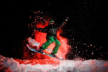 Active female snowboarder dressed in a green sportswear jumping under the snowの写真素材