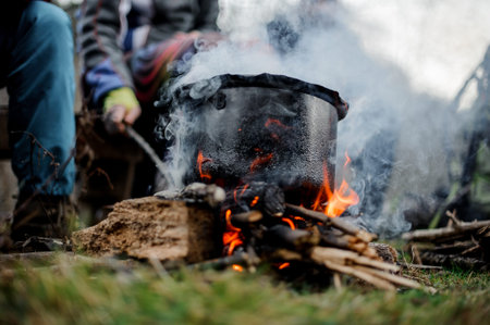 Black pan standing on the bonfire on the background of the group of people