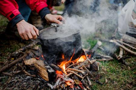 Man placing a cover on the black pan standing on the bonfireの写真素材