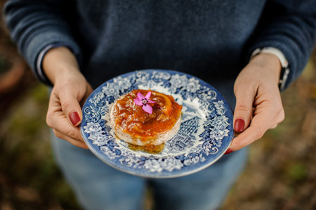 Woman holding a blue ornate plate with a delicious orange jam on the bread