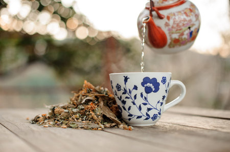 Tea is poured from a teapot with a red pattern into the glass