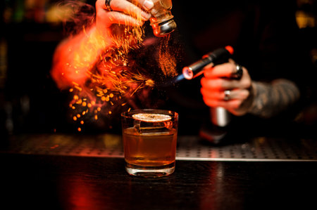 Bartender adding to a cocktail spice and flame it