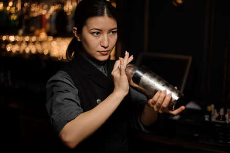 Bartender girl mixing a cocktail in a steel shakerの写真素材