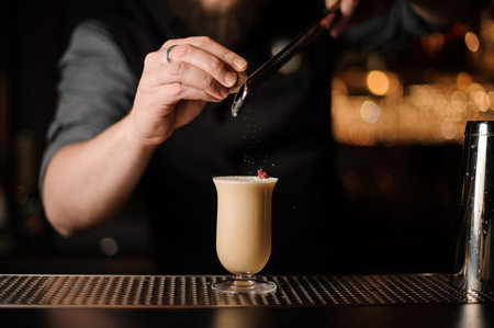 Professional bartender adding to a delicious cocktail grated nutmeg