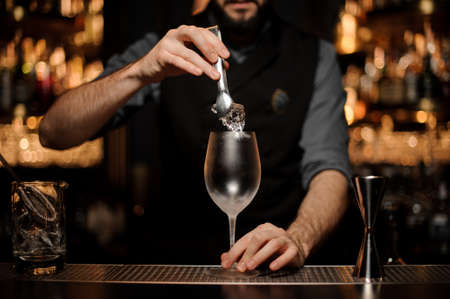Bartender with a beard puts ice in glassの写真素材
