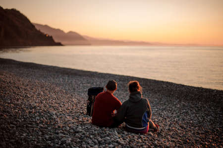 Young romantic happy couple sitting on the beachの写真素材
