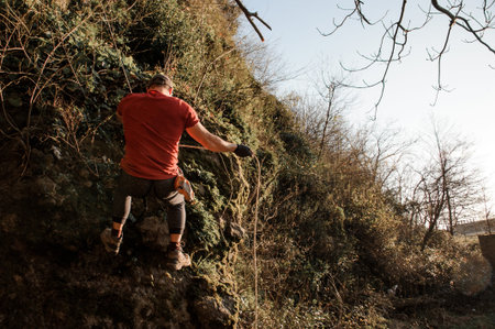 Man equipped with a rope climbing on the rock