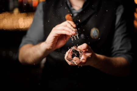 Professional male bartender making an appropriate form to the ice cube with the special toolの写真素材