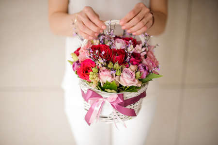 Girl holding a beautiful basket of tender pink and red flowersの写真素材