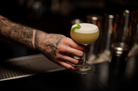 Bartender holding an alcohol cocktail in his handsの写真素材