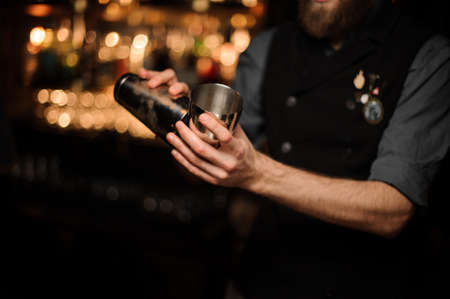 Bartender pouring cocktail with in a steel shakerの写真素材