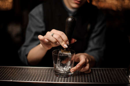 Bartender adds ice in glass with an ice pickの写真素材