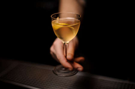 Close-up of alcohol cocktail with lemon rind in bartenders handの写真素材