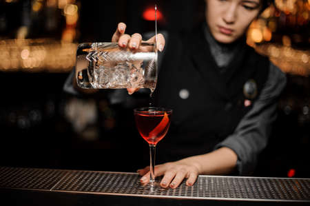 Bartender making alcohol cocktail using glass with strainerの写真素材