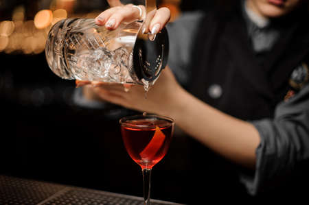 Close shot of bartender pouring cocktail with strainerの写真素材
