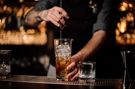 Male bartender stirring alcohol cocktail with bar spoonの写真素材