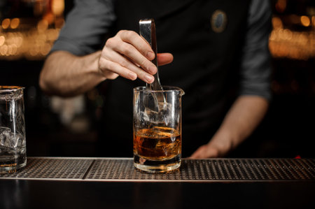 Bartender adding ice in glass with ice tongs