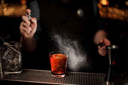 Close-up of bartender making an alcohol cocktail using sprayerの写真素材