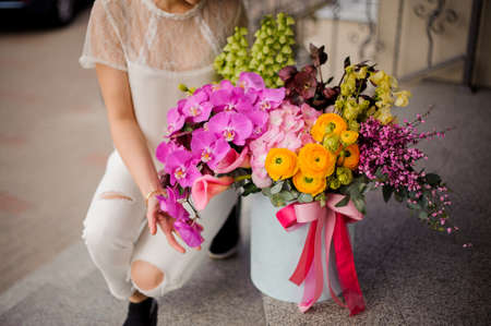 Girl sitting near a spring box of tender yellow, green and pink flowersの写真素材