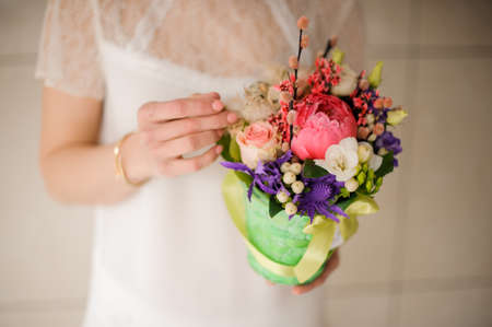 girl holding a spring green pot of tender pink, white and violet flowersの写真素材