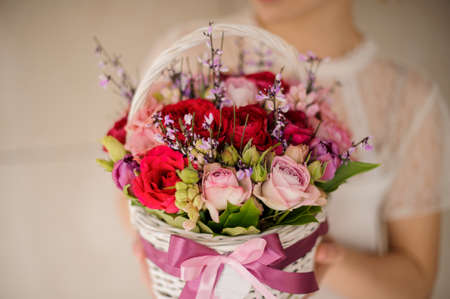 Girl holding a spring white basket of red and pink rosesの写真素材