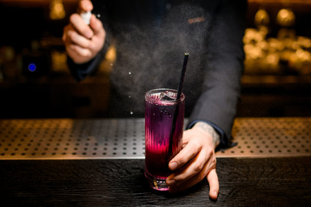 Close-up of bartender spraying to the alcohol cocktailの写真素材