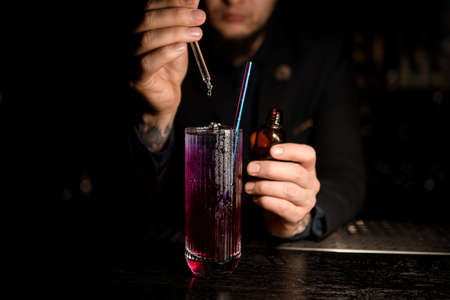 Male Bartender making alcohol cocktail with dropperの写真素材