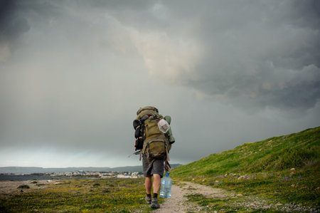 Back view man walking with a hiking backpack on the coastの写真素材