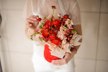 Young woman holding a red velvet box of scarlet and pink flowersの写真素材