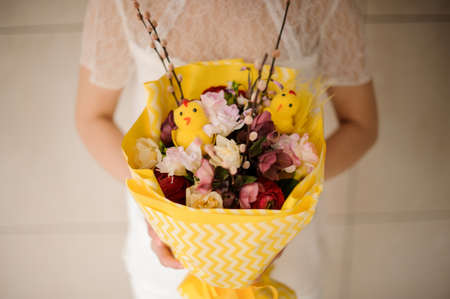 girl holding a spring bouquet of pink and dark flowers in yellow paperの写真素材
