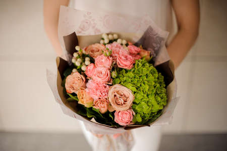 Girl holding a bouquet of tender rose color creamy and green spring flowersの写真素材