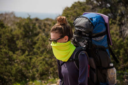 Girl standing with a hiking backpack and special mask from dustの写真素材