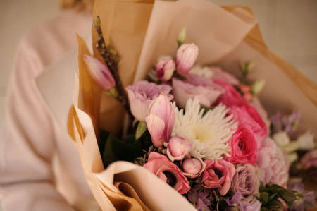 Woman in the coat holding a bouquet of tender color pink flowersの写真素材