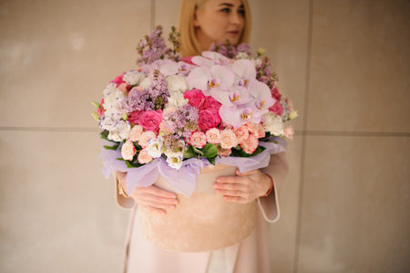 Girl holding a huge spring box of tender multicolored pink flowers