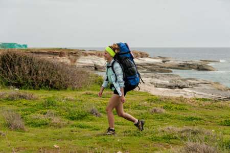 Smiling woman walking on the rocks with hiking backpack