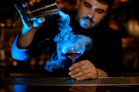 Bartender uses shaker to make an alcohol cocktail