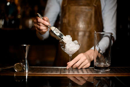 Professional male bartender putting crushed ice to the glassの写真素材