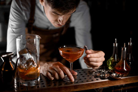 Attractive bartender putting berry on the skewer on the cocktail glassの写真素材
