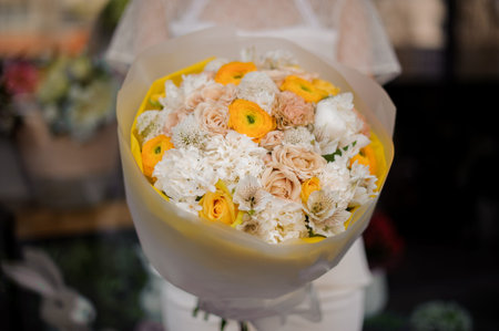 Girl holding a bouquet of yellow peony roses and white hyacinth wrapped in tender color paperの写真素材