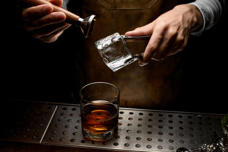 Bartender taking ice cube off ice pickerの写真素材