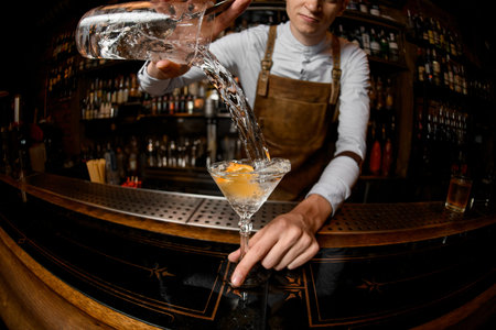 Young bartender pouring alcohol from a jar