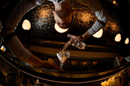 Young bartender pouring alcohol from the jarの写真素材
