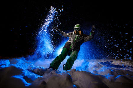 Active female snowboarder dressed in a green sportswear riding on the snowの写真素材
